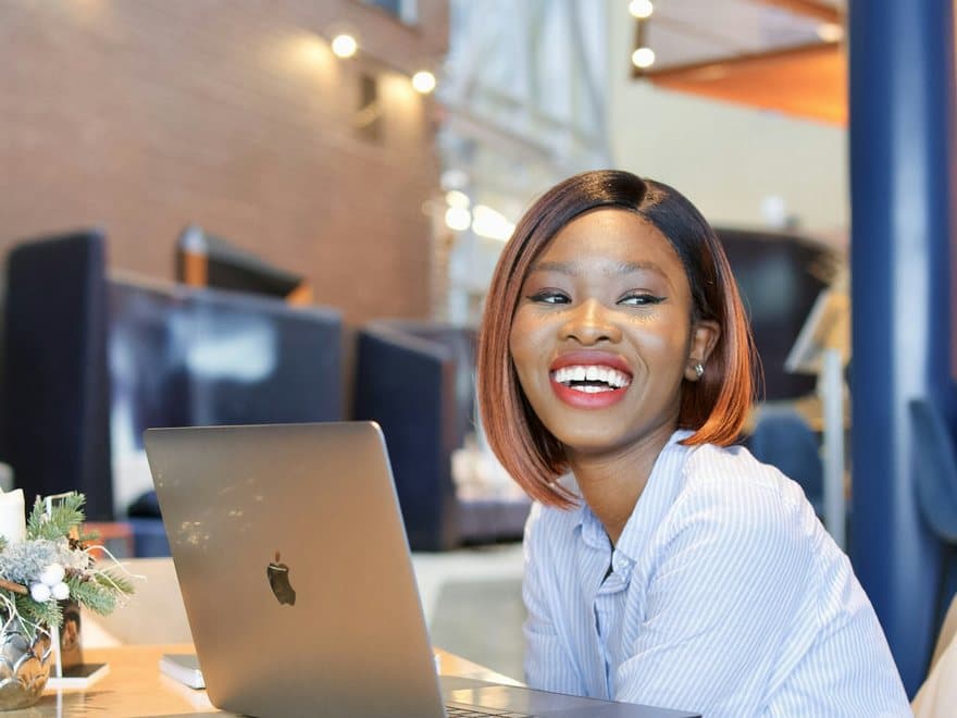 A freelancer laughing at her laptop in a café