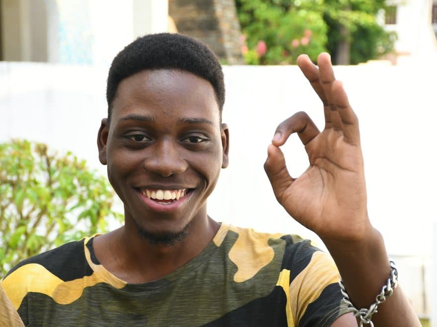 A young man grinning and giving the OK sign